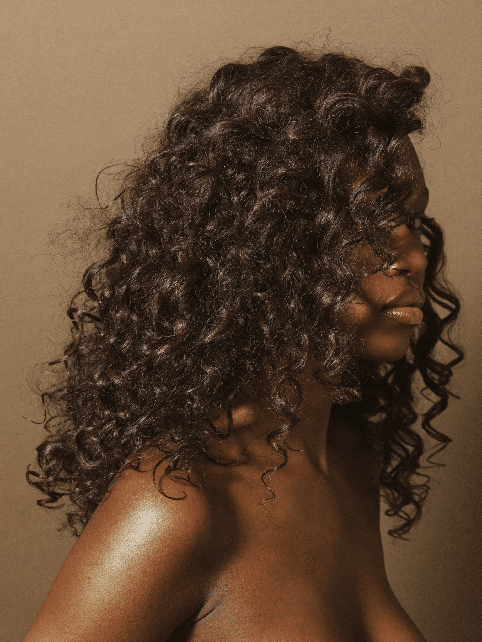 Voluminous defined wash-and-go curls with high shine, photographed three-quarter on.